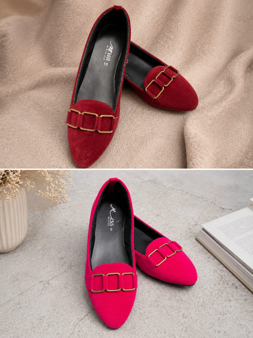 A pair of pointed-toe flats shown in two color variants: deep red and bright pink, both featuring a double gold buckle detail across the vamp. The top image shows them on a beige fabric background, and the bottom image shows them on a gray stone-textured surface next to a book and vase.